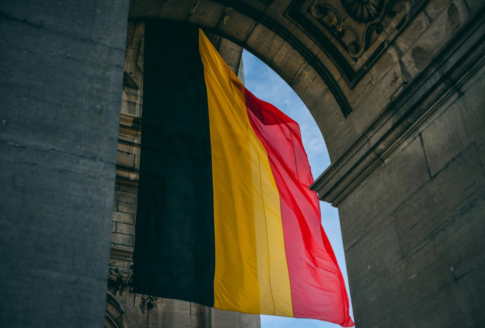 Vibrant Belgian flag under iconic archway in Brussels, symbolizing national pride.